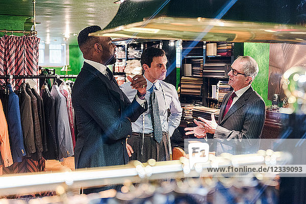 Tailors and customer having discussion in traditional tailors shop