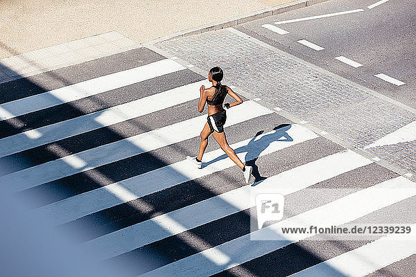 Junge Frau rennt auf Zebrastreifen