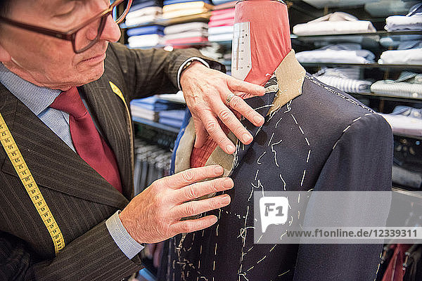 Schneider bereitet maßgeschneiderte Anzugjacke auf Schneiderpuppe vor