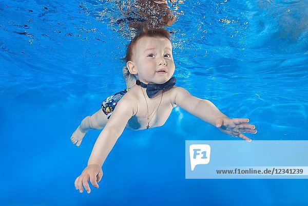Litle boy swim underwater in the pool.