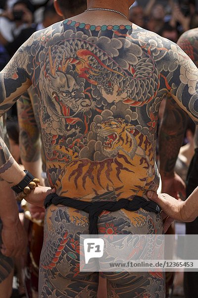 A man showing his full body tattooed  possibly a member of the Japanese mafia or Yakuza  attends the Sanja Matsuri in Asakusa district on May 20  2018  Tokyo  Japan. The Sanja Matsuri is one of the largest Shinto festivals in Tokyo  and it is held in Tokyo's Asakusa district for three days around the third weekend of May. Large groups of people dressed up traditional clothes carry Mikoshi (sacred portable shrines) between the streets near to Sensoji Temple to bring blessing and fortune to the inhabitants of the neighboring community at Asakusa during the second and third day of the festival. The annual festival attracts millions of visitors every year.