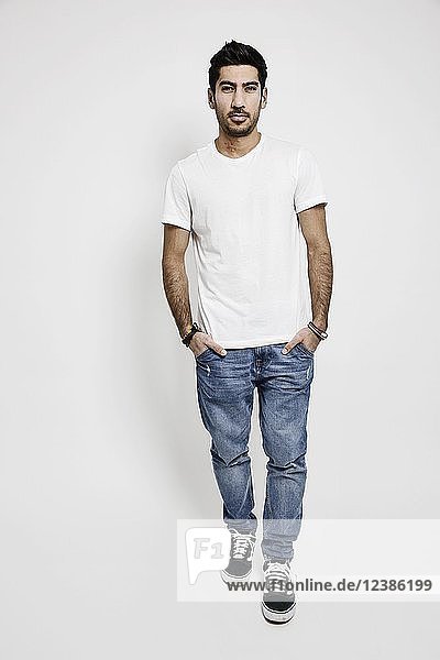 Junger Mann  weißes T-Shirt  Jeans und Turnschuhe  Studioaufnahme