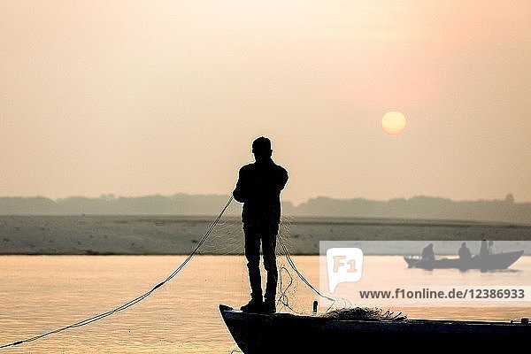 Fischer wirft sein Netz bei Sonnenaufgang am Ganges aus  Varanasi  Uttar Pradesh  Indien  Asien