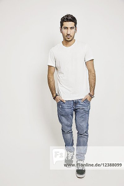 Young man  white T-shirt  jeans and sneakers  studio shot