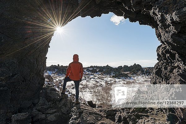 Man in a rock arch with sunbeams  volcanic landscape  volcanic area Krafla  Dimmuborgir National Park  Mývatn  Iceland  Europe