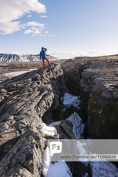 Mann mit Blick nach draußen  stehend an der Kontinentalspalte zwischen der nordamerikanischen und der eurasischen Platte  Mittelatlantischer Rücken  Rift Valley  Silfra-Spalte  Krafla  Nordisland  Island  Europa