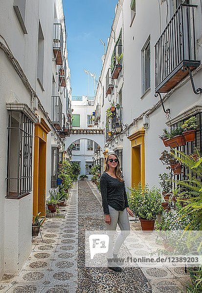 Tourist in einer mit Blumen und Pflanzen geschmückten Gasse mit weißen Häusern  Calle Indiano  Córdoba  Provinz Cordoba  Andalusien  Spanien  Europa