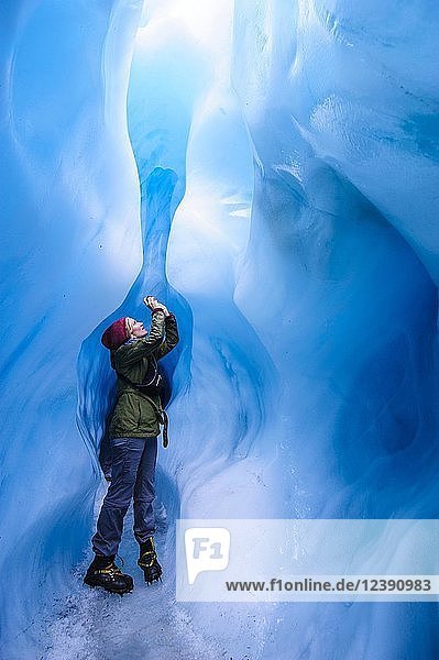 Frau beim Fotografieren in einer Eishöhle im Fox Glacier  Südinsel  Neuseeland  Ozeanien