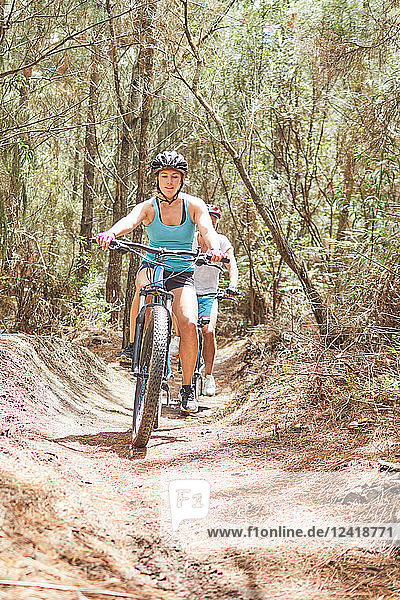 Woman mountain biking on sunny trail in woods
