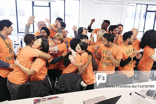 Enthusiastic hackers celebrating  coding for charity at hackathon
