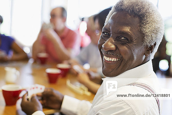 Portrait happy senior man playing cards with friends in community center