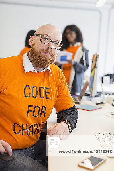 Portrait confident hacker coding for charity at hackathon
