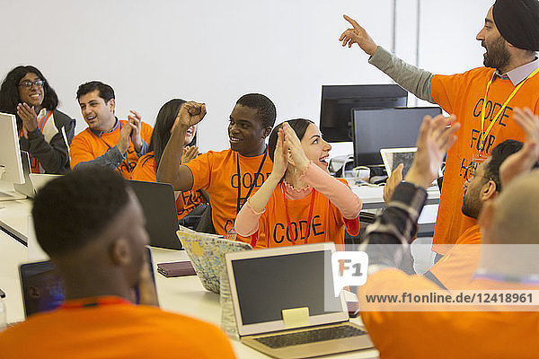 Happy hackers cheering and celebrating  coding for charity at hackathon