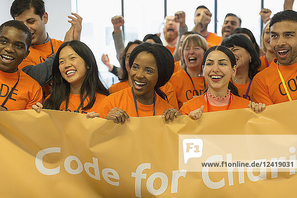 Happy hackers with banner coding for charity at hackathon