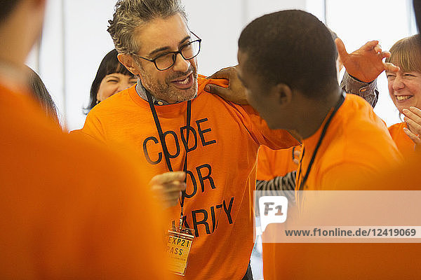 Happy hackers hugging  coding for charity at hackathon