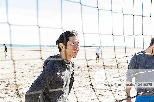 Smiling man playing beach volleyball on sunny beach