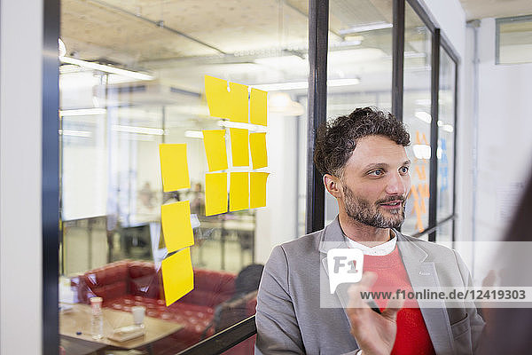 Creative businessman brainstorming with adhesive notes in office