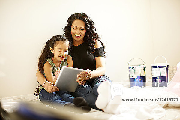 Mother and daughter with digital tablet preparing painting project