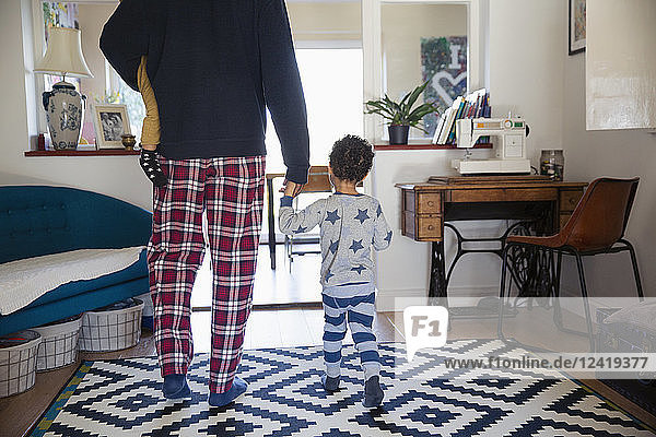 Vater und Söhne im Pyjama gehen im Wohnzimmer spazieren