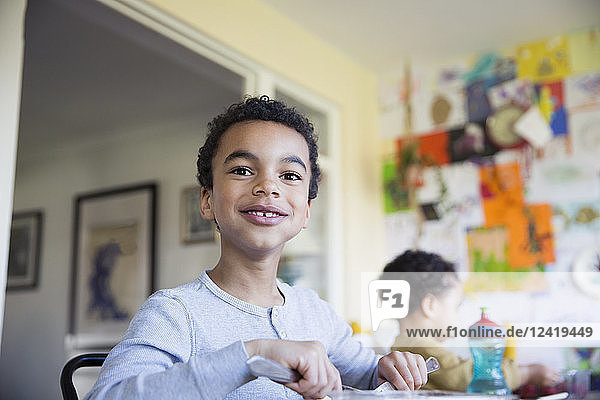 Portrait confident boy eating at dining table