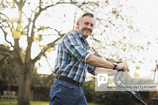 Portrait smiling senior man mowing lawn