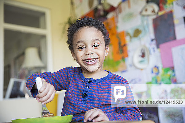Porträt eines lächelnden  selbstbewussten Kleinkindes beim Essen