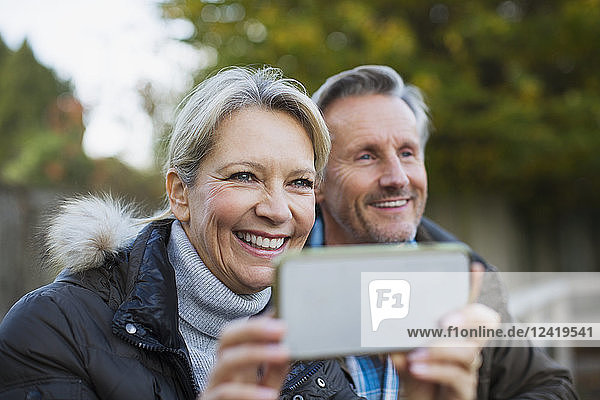 Happy mature couple using camera phone