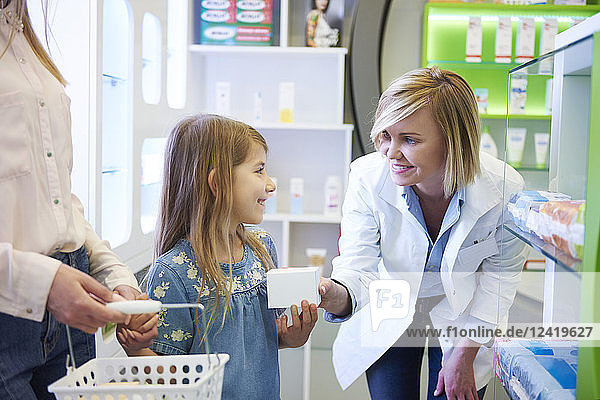 Pharmacist advising mother and daughter in pharmacy