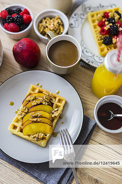 Breakfast table with waffle garnished with nectarine  walnuts and maple sirup