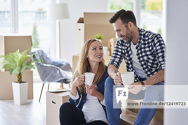 Man and pregnant woman moving into new flat having a coffee break