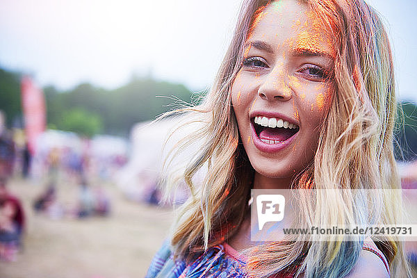 Portrait of happy young woman having fun with colorful powder