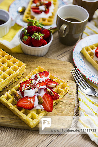 Waffle garnished with strawberries  Greek yogurt and almonds on breakfast table