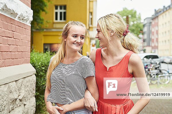Two happy young women arm in arm in the city