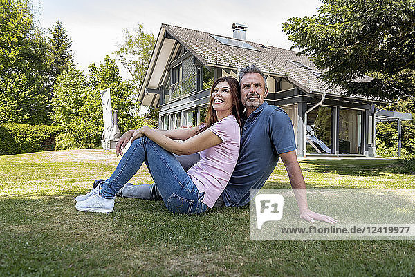 Happy couple sitting in garden of their home