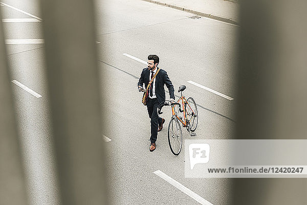 Businessman with bicycle and cell phone walking on the street