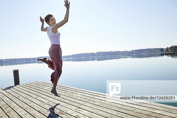 Happy woman jumping in the air on jetty