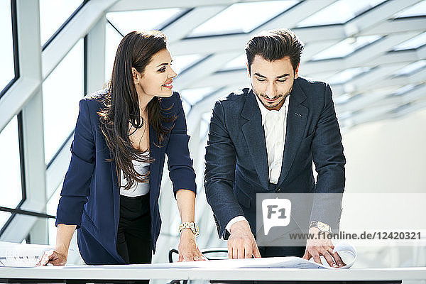 Smiling businesswoman and businessman looking at plan in office