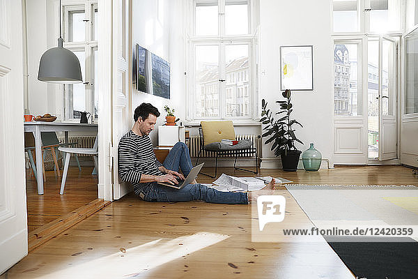 Man sitting in foor  using laptop  working from home