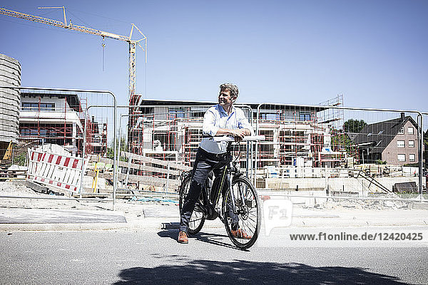 Man with e-bike on construction site looking around