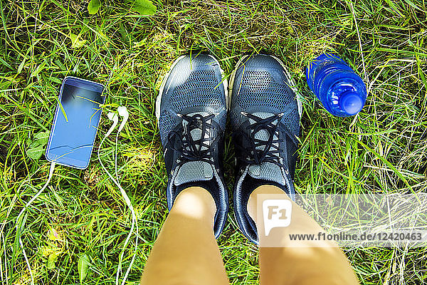 Running shoes  smartphone with earphones  water bottle  overhead view
