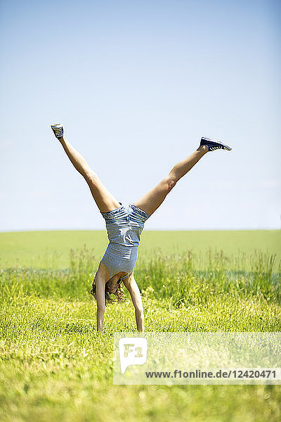 Young woman doing handstand on meadow