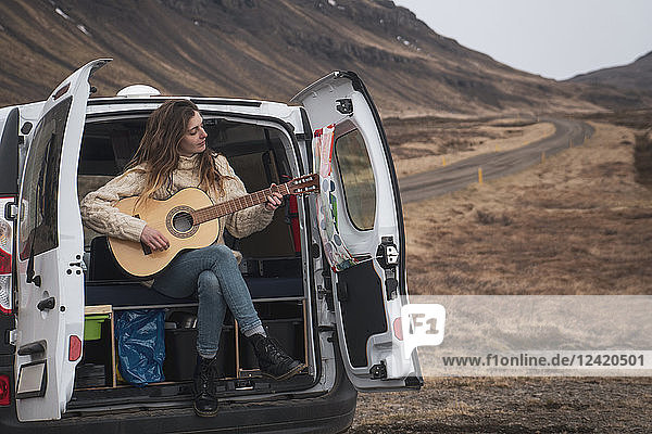 Iceland  woman in front of van playing guitar