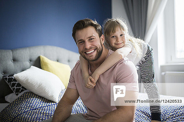 Happy father and daughter sitting on bed  embracing