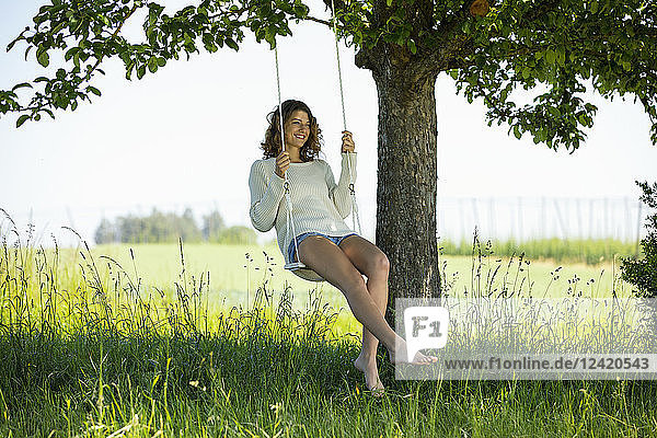 Smiling young woman sitting on swing