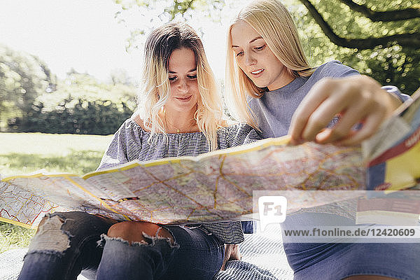 Two young women looking at map in a park