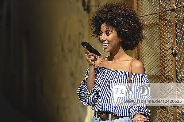 Portrait of fashionable young woman with curly hair on the phone