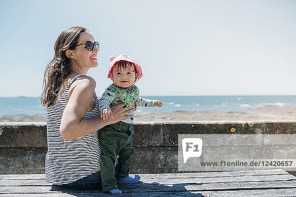 France  content mother and baby girl on a bench at beach promenade