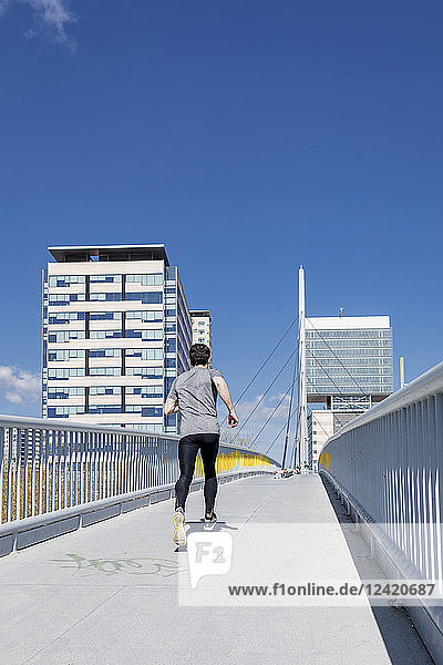 Sportive man runinng on a bridge in the city