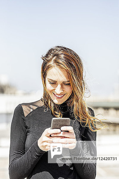 Portrait of smiling woman using smartphone outdoors
