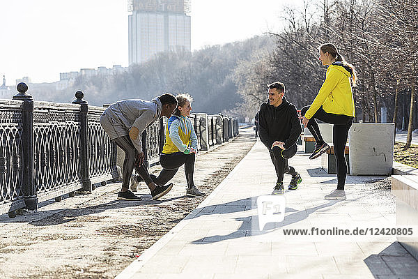 Friends doing stretching exercise on promenade in the city